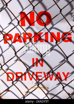 Non c'è parcheggio nel cartello del vialetto con le ombre della recinzione della catena Chainlink Foto Stock