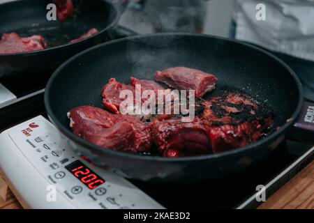Carne di manzo cruda per cucinare la bistecca. Cottura della bistecca alla griglia in una padella durante una lezione di cucina. Bistecca bruciata. Cucina a casa, cibo fatto in casa. Foto Stock