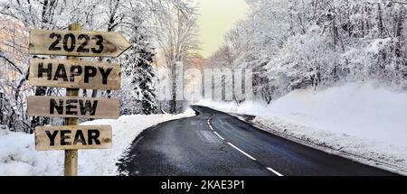 palo direzionale in legno con freccia che indica una strada che attraversa una foresta innevata in montagna Foto Stock