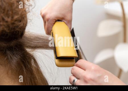 Stiratura dei capelli al salone di bellezza. Palo per il trattamento di cheratina e proteine con utensile professionale per il trattamento di capelli e proteine a ultrasuoni. Foto Stock