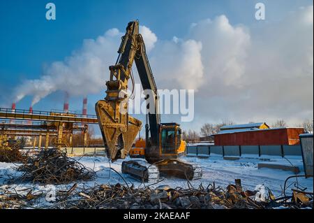 Le cesoie idrauliche sull'escavatore rimuovono cemento e metallo Foto Stock