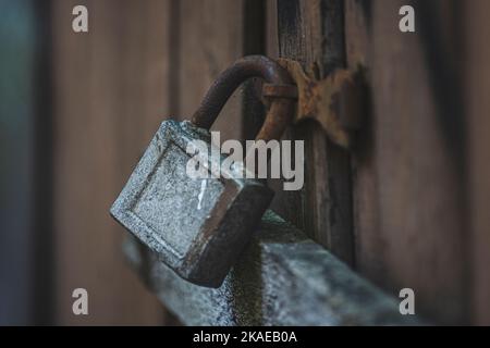 Vecchio lucchetto arrugginito e frammenti di metallo su vecchie porte di legno colorate Foto Stock