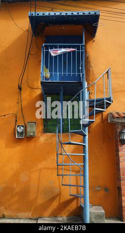 Un'immagine verticale di un bellissimo edificio arancione con scale a spirale che salgono all'ingresso Foto Stock