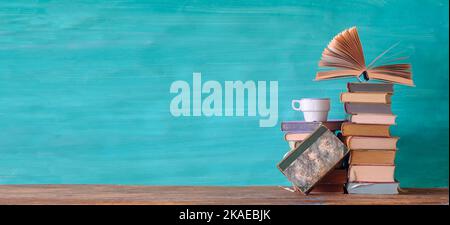 Libro aperto su un mucchio di vecchi libri e una tazza di caffè, educazione, lettura, conoscenza concept.Panoramic, grande spazio di copia. Foto Stock
