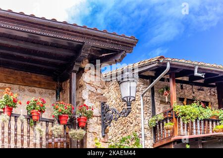 Le pittoresche case in pietra con fiori e stradine strette nel villaggio di Barcena Mayor in Spagna Foto Stock