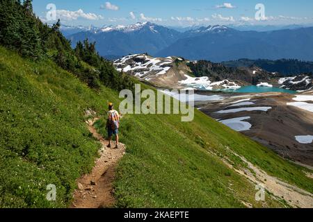 WA22688-00...WASHINGTON - Hiker sul sentiero Ptarmigan Ridge che si affaccia sul lago 14-Goat nella zona di Mount Baker Wilderness. Foto Stock