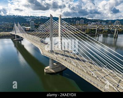 Tilikum Crossing, Bridge of the People è un ponte sospeso sul fiume Willamette a Portland, Oregon, Stati Uniti. È stato progettato da TriMet, l'autorità regionale di transito dell'area metropolitana di Portland, per i treni passeggeri della linea leggera MAX Orange Line. Il ponte serve anche autobus urbani e il Portland Streetcar, nonché biciclette, pedoni e veicoli di emergenza. Auto private e camion non sono ammessi sul ponte. È il primo ponte principale degli Stati Uniti che è stato progettato per consentire l'accesso a veicoli di transito, ciclisti e pedoni, ma non automobili. Foto Stock