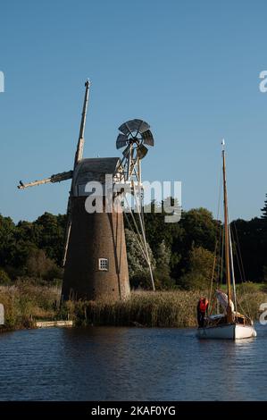 Tappeto erboso Fen mulino a vento drenante e barca a vela sul fiume ANT, Norfolk Broads Foto Stock