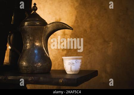 Dubai, Emirati Arabi Uniti - 12th ottobre 2022: Caffè vista laterale allestito da una tazza di tè bianco con tradizionale dallah arabo nel museo del caffè di Dubai Foto Stock