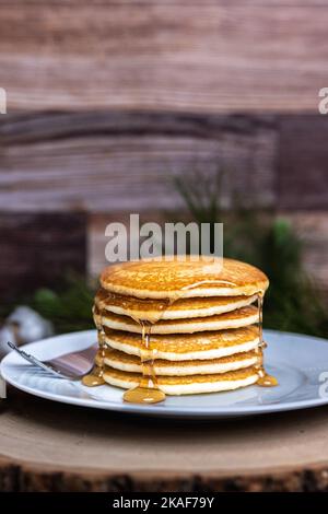 Un piatto grande di frittelle con una forchetta e sciroppo versato sopra Foto Stock