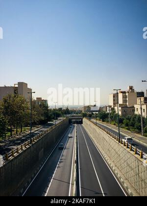 Un colpo verticale di strada a due vie che conduce ad un tunnel in una città sotto il cielo blu Foto Stock