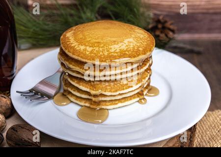 Un piatto grande di frittelle con una forchetta e sciroppo versato sopra Foto Stock