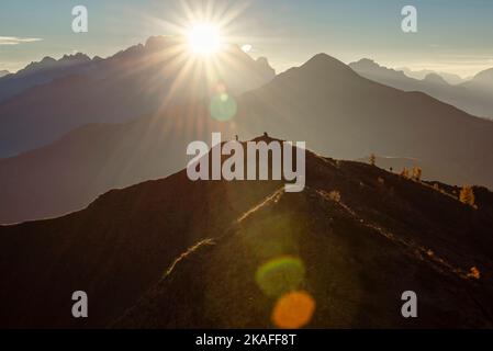 Escursionisti su una cima panoramica al Passo di Giau nella calda retroilluminazione del tramonto sulla cima della Marmolada, Dolomiti, Italia Foto Stock