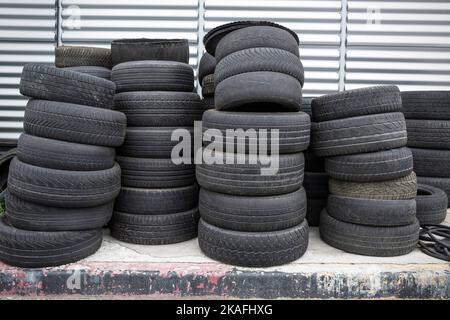 Vecchi pneumatici usati impilati. Pile nere di pneumatici usati Foto Stock