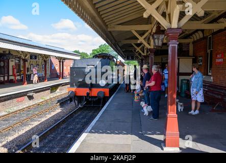 Un treno a vapore vintage che si avvicina ai passeggeri in attesa sulla piattaforma 1 alla stazione di Sheffield Park sulla linea ferroviaria Bluebell, East Sussex, Inghilterra. Foto Stock