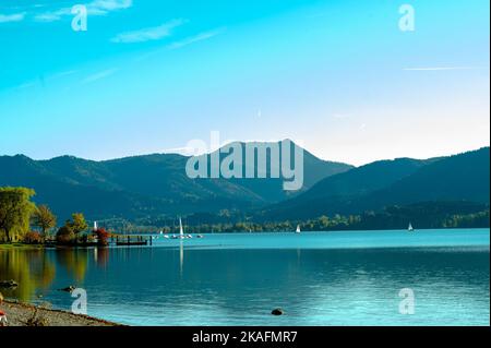 Una vista di un lago e di una montagna nella panoramica e bella Tegernsee, Germania contro un vibrante cielo blu Foto Stock