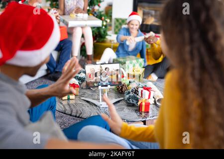 Amici diversi con decorazioni natalizie che hanno videochiamata con amici diversi felici Foto Stock