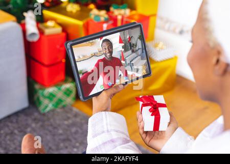 Donna afroamericana con decorazioni natalizie che hanno videochiamata con felice uomo afroamericano Foto Stock