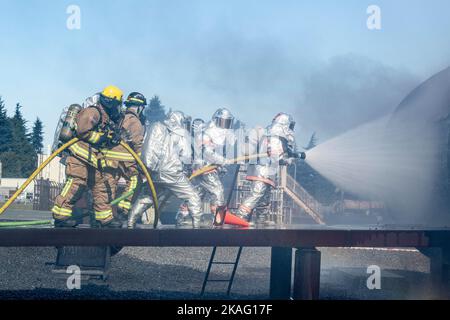 Vigili del fuoco della Japanese Air Self-Defense Force e 374th Civil Engineer Squadron team fino a spruzzare acqua su un incendio simulato aereo durante un addestramento bilaterale alla Yokota Air base, Giappone, 26 ottobre 2022. La pratica di tecniche antincendio standardizzate tra gli Airmen statunitensi e giapponesi ha offerto a entrambe le parti l'opportunità di affinare le capacità congiunte e di costruire partnership più solide. (STATI UNITI Air Force foto di Machiko Arita) Foto Stock