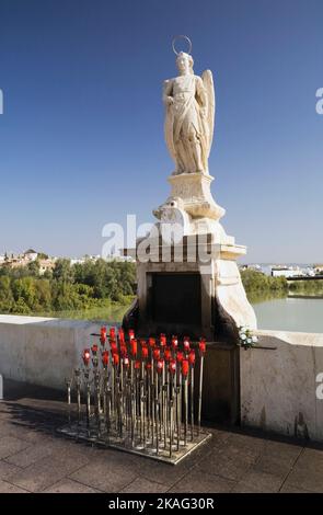 Statua e candele votive sul ponte romano che attraversa il fiume Guadalquivir a Cordova, Spagna. Foto Stock