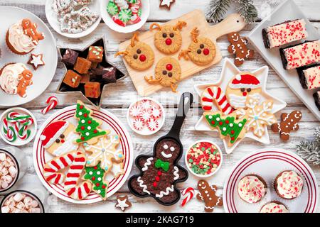 Dolce di Natale carino e cookie tavola scena. Vista dall'alto verso il basso su uno sfondo rustico di legno bianco. Concetto di cottura di festa di divertimento. Foto Stock