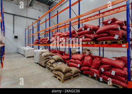 Borse con produzione su scaffali in magazzino. Sacchetti con chicchi di caffè o zucchero o altro Foto Stock