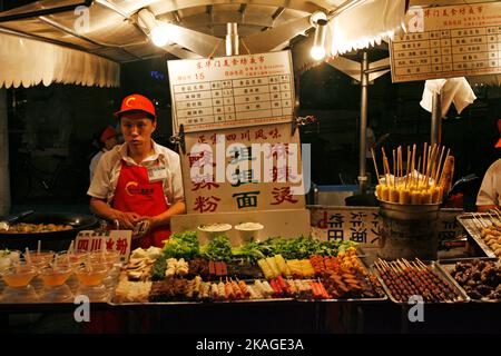 Un fornitore attende i clienti al mercato notturno di Donghuamen a Pechino, in Cina. Foto Stock