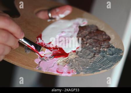 primo piano delle mani di un artista con tavolozza di colori e pennelli Foto Stock