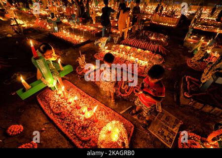 I bambini offrono preghiere accanto alla tomba del loro parente deceduto durante il giorno di tutte le anime in un cimitero. I devoti cristiani si riuniscono nelle tombe dei loro cari in un cimitero con candele e fiori accesi durante la Giornata delle ANIME. Un giorno in cui i cristiani ricordano i loro amici e parenti, che sono passati via. Ciò deriva da un'antica credenza che le anime dei morti ritorneranno, in questo giorno particolare, per consumare un pasto con la loro famiglia & amici. Le candele sono accese per guidare le anime a casa loro per il pasto. (Foto di Avishek Das/SOPA Images/Sipa USA) Foto Stock