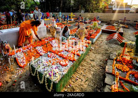 I membri della famiglia cristiana pagano rispetto e offrono preghiere accanto alla tomba del loro parente durante la Giornata delle ANIME. I devoti cristiani si riuniscono nelle tombe dei loro cari in un cimitero con candele e fiori accesi durante la Giornata delle ANIME. Un giorno in cui i cristiani ricordano i loro amici e parenti, che sono passati via. Ciò deriva da un'antica credenza che le anime dei morti ritorneranno, in questo giorno particolare, per consumare un pasto con la loro famiglia & amici. Le candele sono accese per guidare le anime a casa loro per il pasto. (Foto di Avishek Das/SOPA Images/Sipa USA) Foto Stock