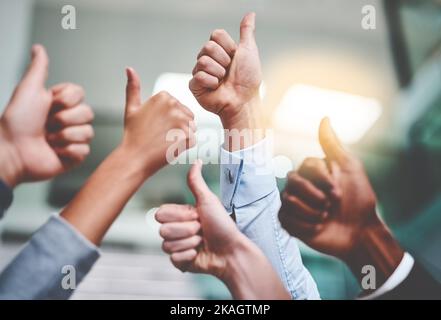 Continuate il lavoro straordinario. Un gruppo di uomini d'affari irriconoscibili che mostra i pollici in un ufficio. Foto Stock