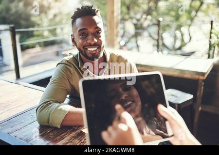 Qual è il tuo speciale del giorno: Un giovane che ordina con un cameriere usando un tablet digitale. Foto Stock
