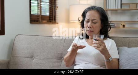 Donna anziana malata tenere pillole sulla mano versando capsule da flacone di farmaco prendere antidolorifico supplemento medicina, anziani Foto Stock