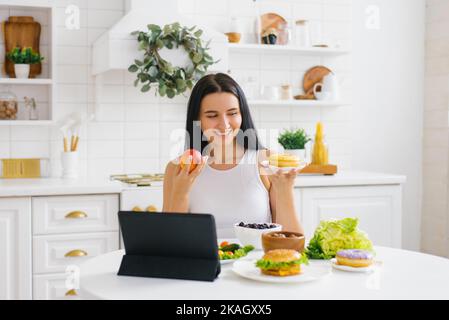 Donna felice nutrizionista tiene una lezione online o conferenza in cucina sul tema di un'alimentazione sana e perdita di peso Foto Stock