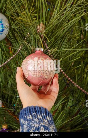 Primo piano donna in maglione decorare l'albero di Natale con palle giocattolo. Natale o composizione di Capodanno. Foto Stock