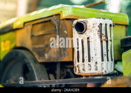 La marmitta del tubo di scarico di un trattore retrostante sullo sfondo di un piccolo motore diesel Foto Stock