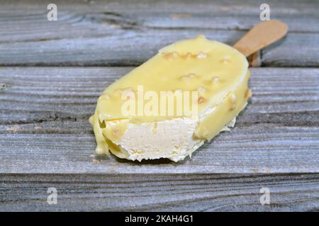 Bastone gelato alla vaniglia rivestito e ricoperto con uno strato di cioccolato bianco con noci, ricco gelato alla vaniglia in cracking cioccolato bianco e. Foto Stock