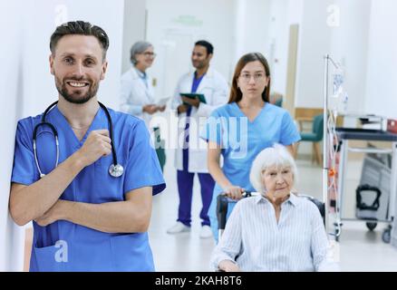 Ritratto del tecnico medico con stetoscopio in piedi davanti al corridoio dell'ospedale con personale medico funzionante. occupazione medica Foto Stock