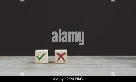 Segno di spunta e segno di croce x su cubi di legno. Blocchi di legno con segno di spunta verde e rosso x. Concetto di presa di decisione positiva o negativa o di scelta o. Foto Stock