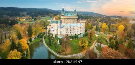 Bojnice castello. Vista aerea panoramica di un romantico castello neogotico fiabesco in un colorato giardino autunnale. Fortificazione, torri e fossato d'acqua. U Foto Stock