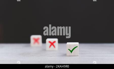 Segno di spunta e segno di croce x su cubi di legno. Blocchi di legno con segno di spunta verde e rosso x. Concetto di presa di decisione positiva o negativa o di scelta o. Foto Stock