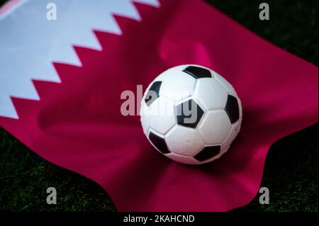 Nazionale di calcio del Qatar. Bandiera nazionale su erba verde e palla da calcio. Carta da parati da calcio per Campionato e Torneo nel 2022. Internazionale Foto Stock