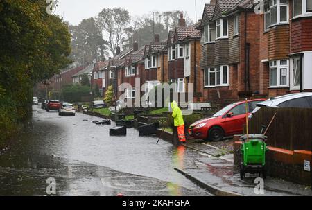 Brighton UK 3rd novembre 2022 - Un membro del personale del consiglio tenta di ripulire le acque alluvionali in una strada a Moulsecoomb , Brighton, dove i bidoni dei rifiuti domestici galleggiano lungo la strada durante le forti piogge. : Credit Simon Dack / Alamy Live News Foto Stock