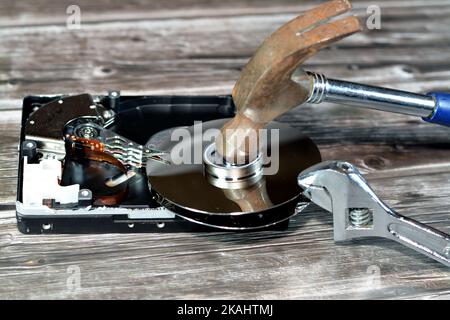 Chiave a bussola e martello in acciaio con dischi HDD, disco rigido smontato componenti danneggiati, manutenzione computer, ripristino, cancellazione dati, dati k Foto Stock