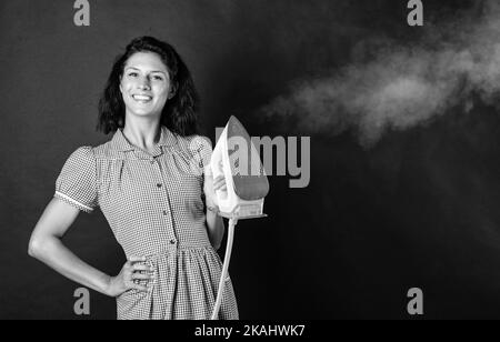 Ferro da stiro per voi. pinup ragazza preparare la stiratura. vintage signora tenere ferro moderno. Vita quotidiana e casalinghi. Donna retrò con ferro. Cameriera allegra Foto Stock