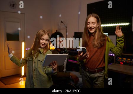 Due giovani artisti che provano, produttore di musica che ascolta canzone Foto Stock