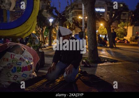 L'uomo prega nel Victoria Park, nel centro della capitale greca, Atene, il 16 marzo 2016. Centinaia di migranti trascorrono, in questo piccolo parco, molti giorni con la speranza una notizia migliore sulla crisi dei migranti. Foto Stock