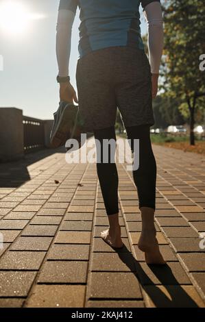 Uomo runner con scarpe sportive a piedi sul lungomare Foto Stock