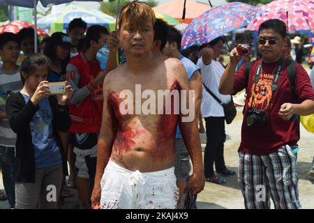 PROVINCIA DI PAMPANGA, Filippine - le persone scattano foto del sangue indietro di un penitente durante i riti quaresimale a San Fernando City, provincia di Pampanga il Venerdì Santo, 25 marzo 2016. L'autoflagellazione è uno dei tanti atti di penitenza compiuti dai cattolici filippini nella speranza di perdono dei loro peccati mentre celebrano il tempo quaresimale. (Foto di George Calvelo/NurPhoto) *** Please use Credit from Credit Field *** Foto Stock