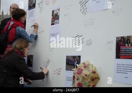 La gente si trova di fronte a un consiglio di amministrazione che porta messaggi in ricordo del deputato laburista ucciso Jo Cox in Piazza del Parlamento di fronte alle Camere del Parlamento nel centro di Londra il 18 giugno 2016. Il presunto assassino del legislatore britannico Jo Cox si è arrangiato contro i traditori durante una breve apparizione in tribunale sabato, mentre la campagna referendaria dell'UE è stata sospesa per un terzo giorno in omaggio al deputato ucciso. Il deputato di 41 anni è stato ucciso e pugnalato per strada in quella che la polizia ha chiamato un attacco di luce naturale 'mirato' il 16 giugno nella sua circoscrizione nel nord dell'Inghilterra, mentre stava arrivando per un incontro con i residenti locali. (PH Foto Stock